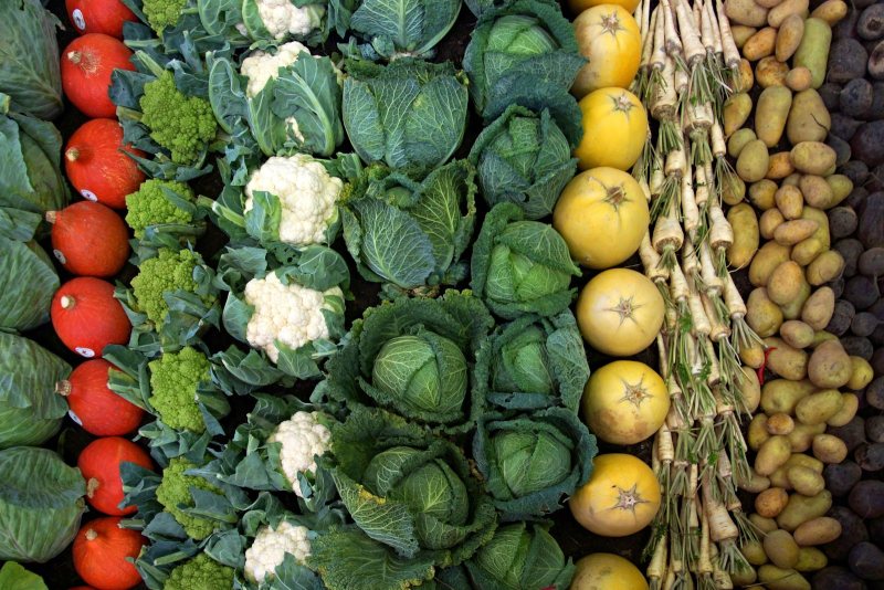 A market display of cabbages, cauliflower, and other vegetables