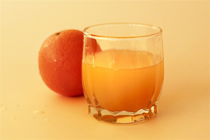 A glass of orange juice next to a whole orange