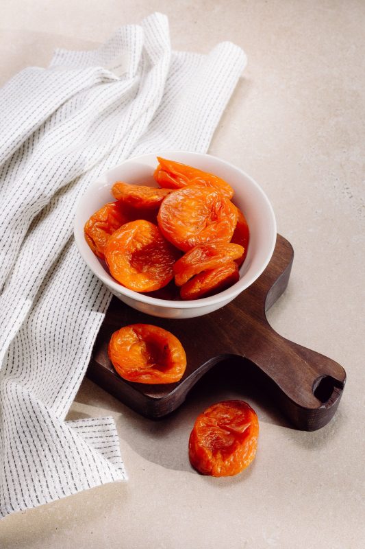 Bright orange dried apricots in a white bowl