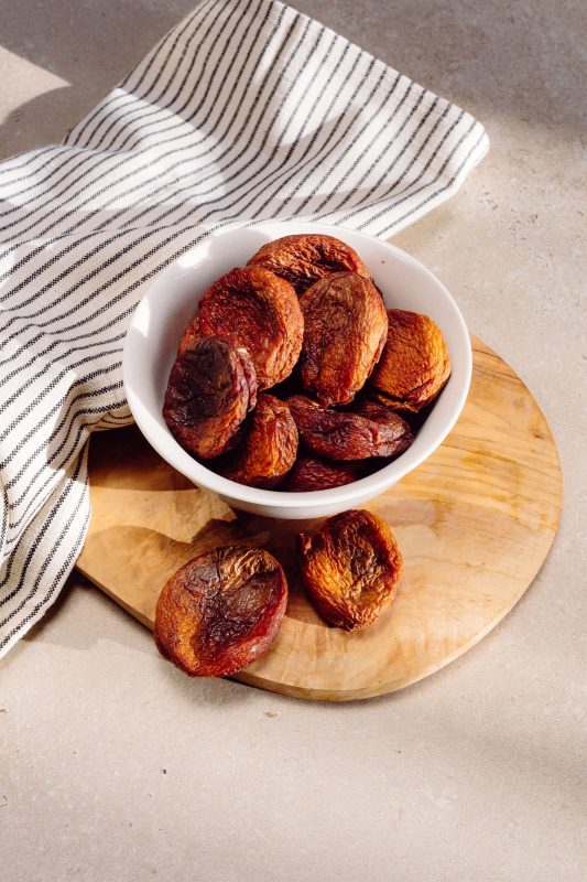 Dark brown dried apricots in a white bowl