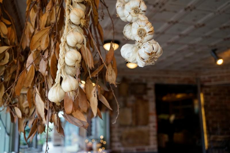 A market stall piled with fresh garlic bulbs and dried stalks