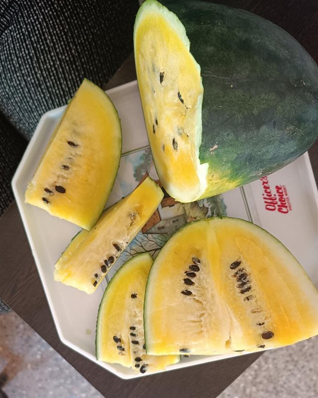 Slices of yellow watermelon with dark seeds on a plate
